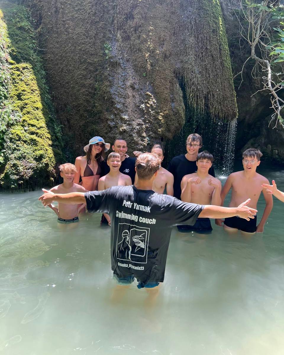 Kids standing in a river pool beneath a waterfall