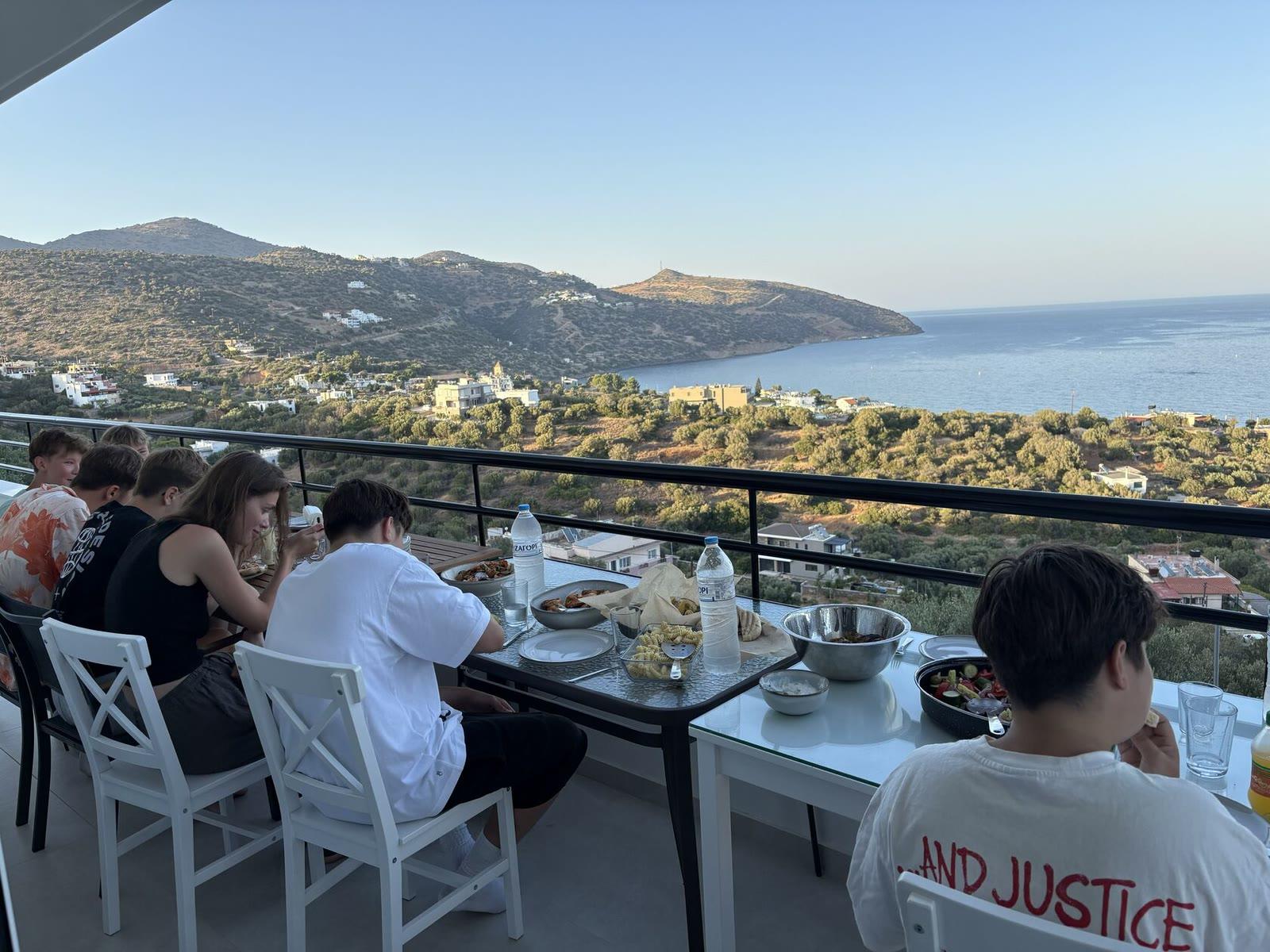 Campers eating together at a terrace table overlooking the sea