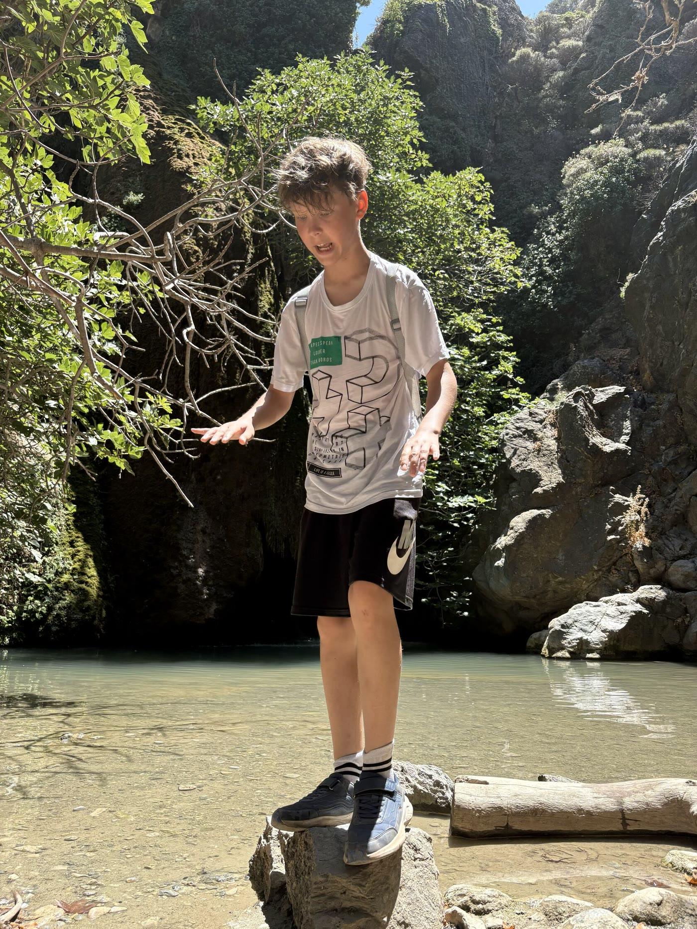 A boy on the stones of a stream in a gorge