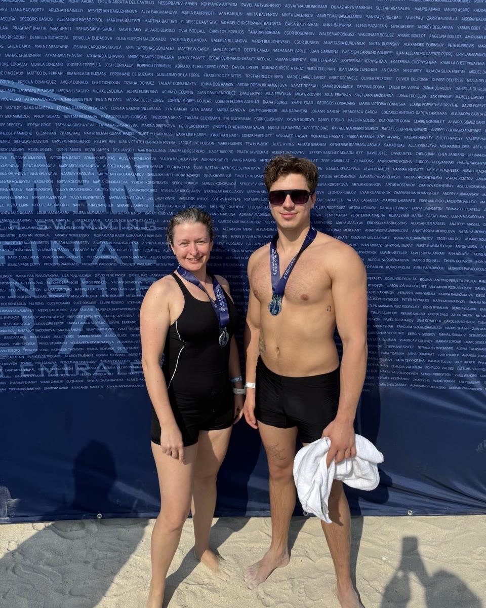 Two swimmers with finisher medals in front of the OCEANMAN backdrop