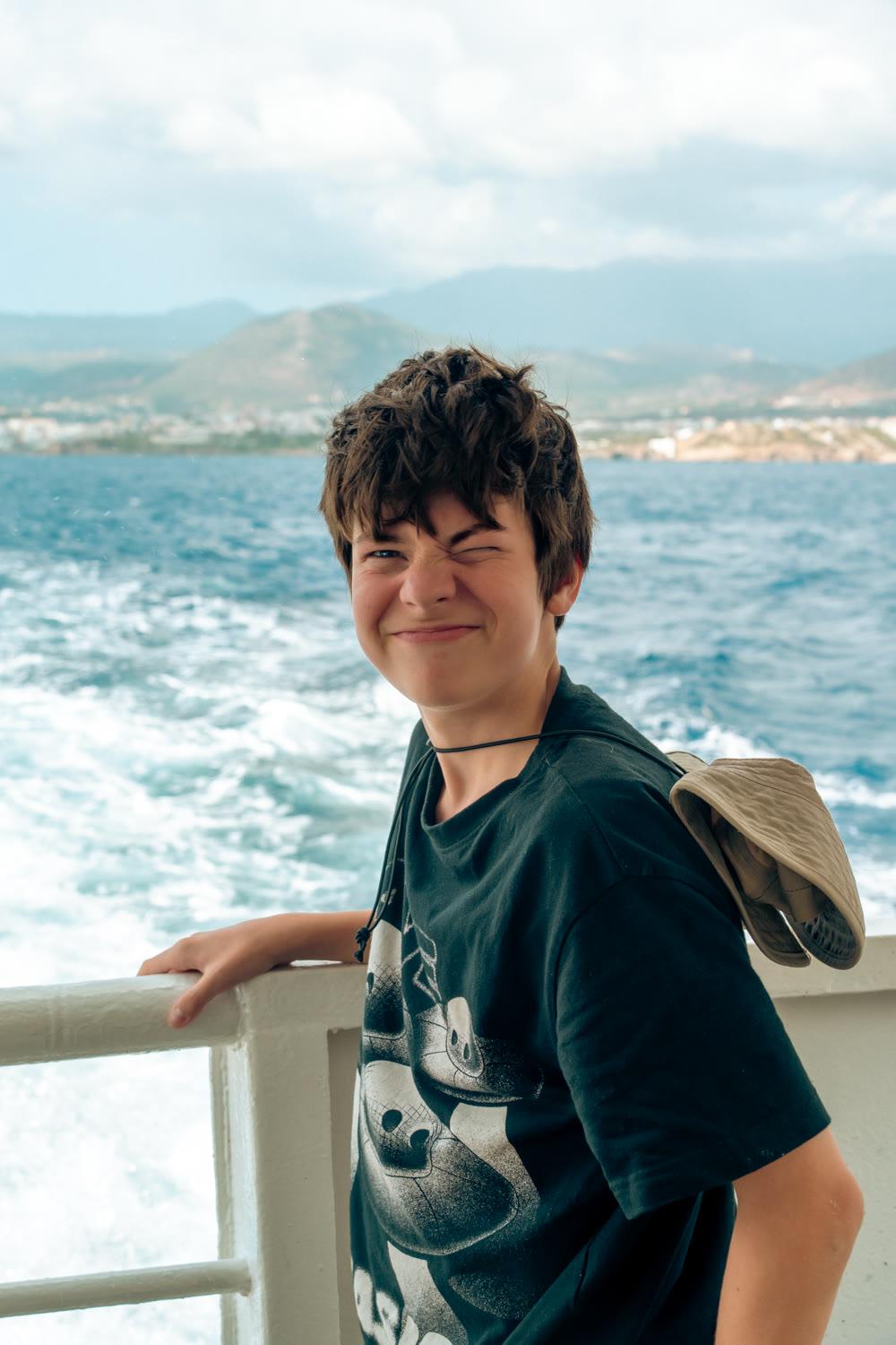 A camper grinning on a boat deck, the wake foaming behind