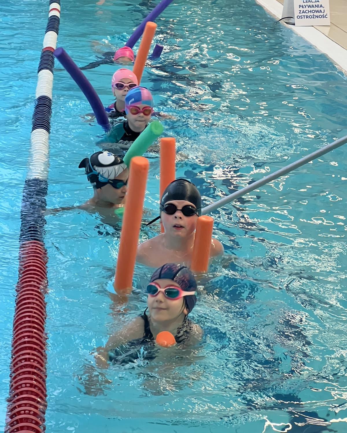 Kids in a group lesson with pool noodles