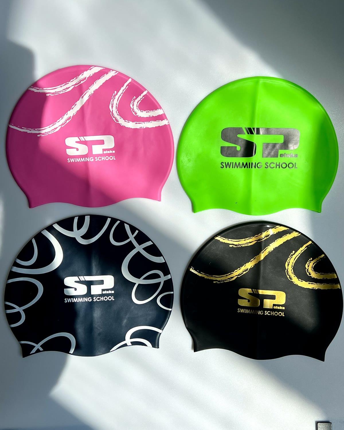 Four SwimPolska silicone caps: pink, green, and two black ones with white and gold prints